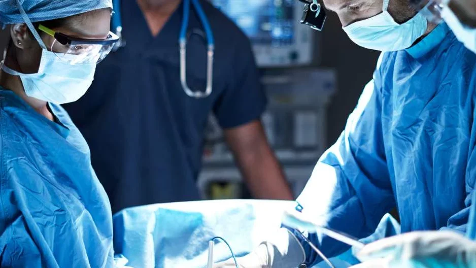 Photo of three medical professionals performing surgery 