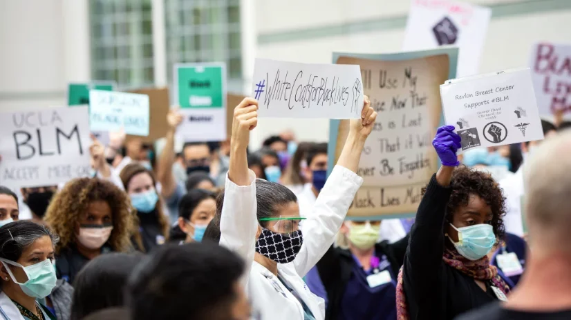 2020 Solidarity Day at UCLA, with a shot of the crowd and a physician holding a sign for #whitecoatsforblacklives