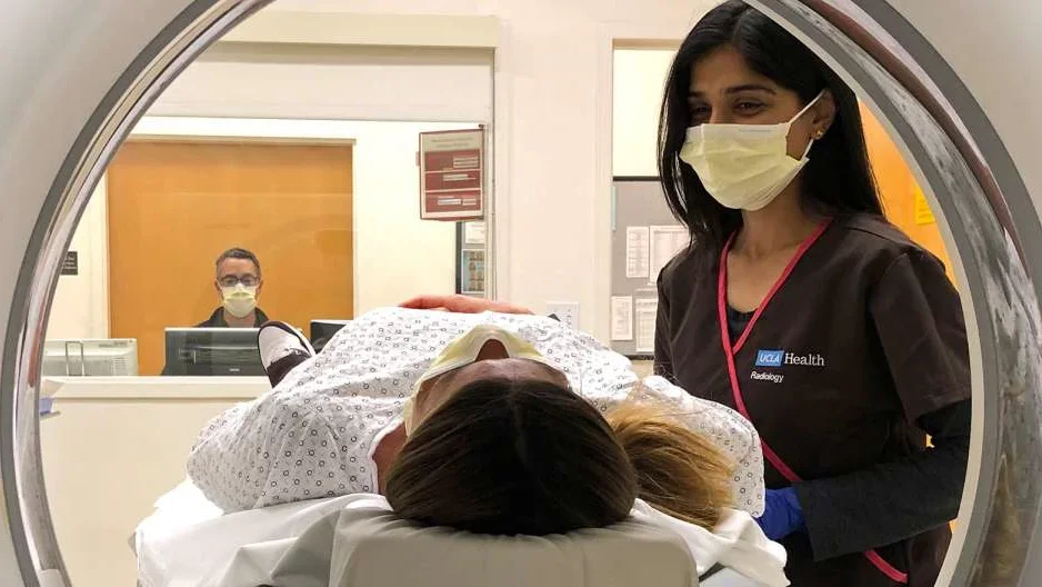 Photo of patient in MRI device with assisting Radiologist 