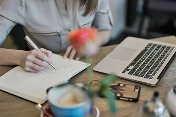 A person at a computer taking notes