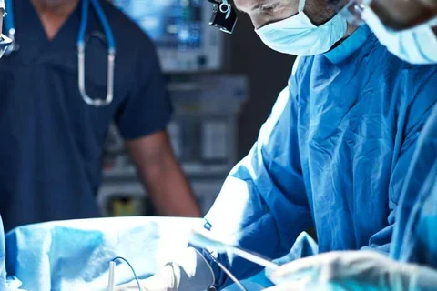 Photo of three medical professionals performing surgery 