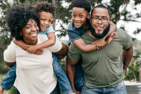 Parents carrying kids on their backs and smiling