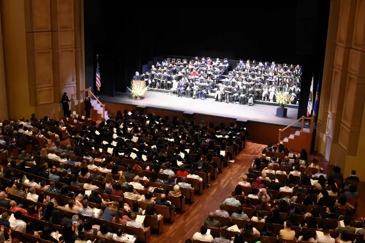 Royce Hall audience and stage filled with people in graduation regalia