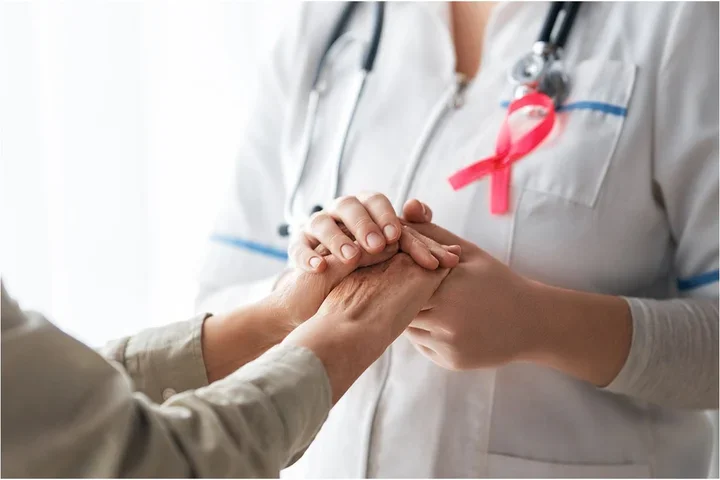 doctor holding hands with pink ribbon