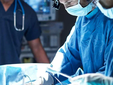 Photo of three medical professionals performing surgery 