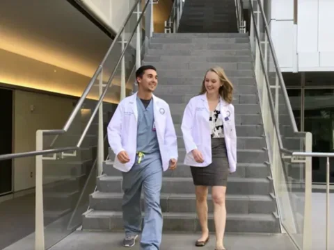 Two medical students walk down the stairs into the courtyard at Geffen Hall, deep in conversation
