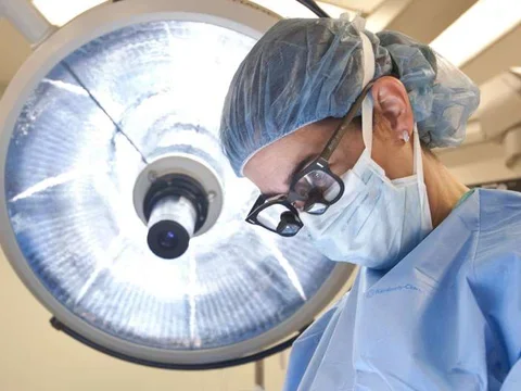 Photo of Doctor in surgery with surgical lamp behind them 