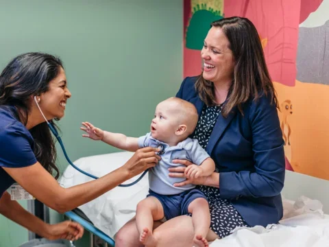 UCLA Medical School Student Doctor Providing Patient Care to Mother With Baby on Lap