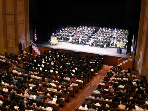 Royce Hall audience and stage filled with people in graduation regalia