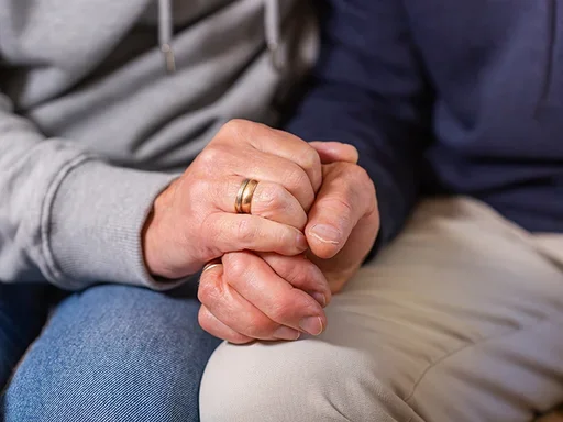 Spouse holding hands resting on legs